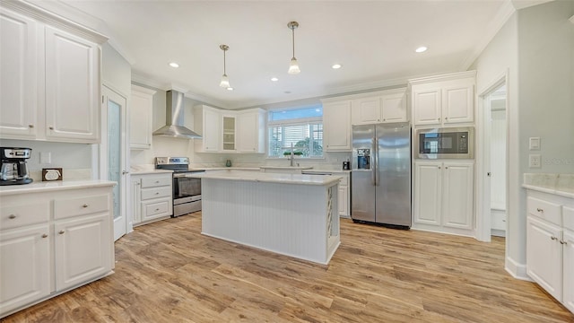 kitchen with wall chimney exhaust hood, light hardwood / wood-style floors, appliances with stainless steel finishes, and hanging light fixtures