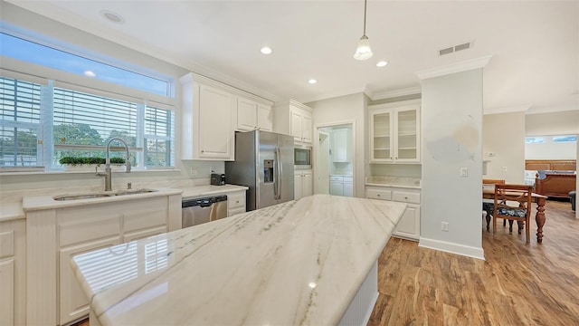 kitchen featuring sink, white cabinetry, hanging light fixtures, light hardwood / wood-style flooring, and appliances with stainless steel finishes