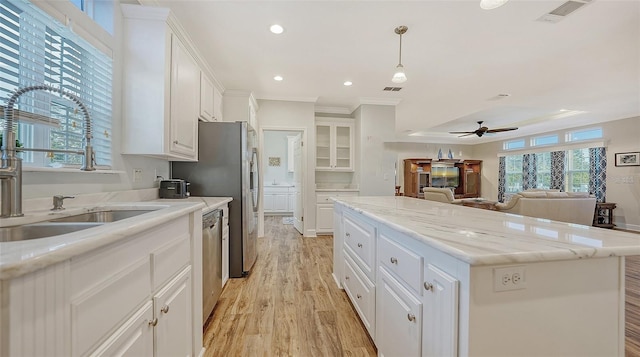 kitchen featuring decorative light fixtures, a center island, sink, and white cabinetry