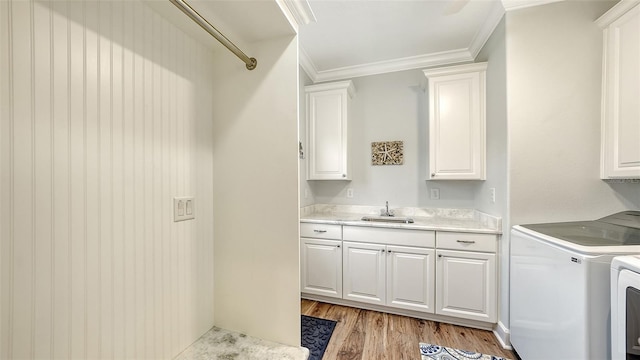 laundry room featuring sink, cabinets, independent washer and dryer, light wood-type flooring, and crown molding