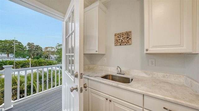 interior space with white cabinets, light stone countertops, and sink