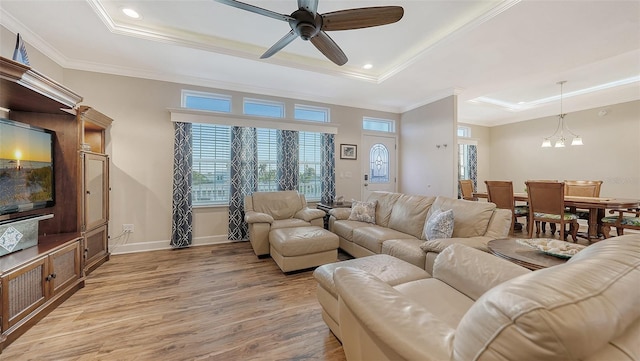 living room with crown molding, light hardwood / wood-style flooring, and a raised ceiling