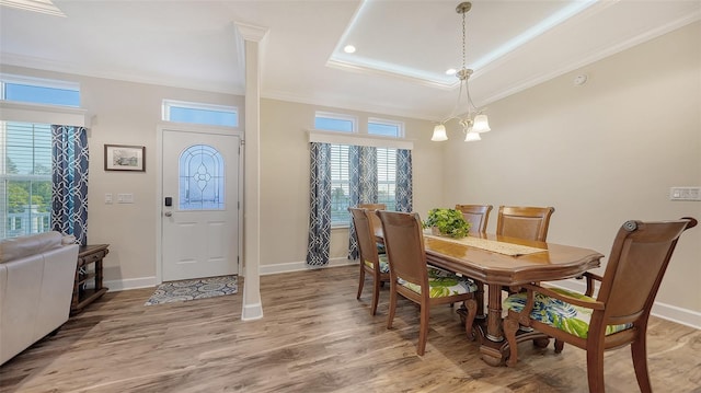 dining area with crown molding, a tray ceiling, a chandelier, and hardwood / wood-style floors