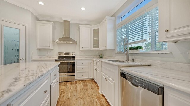 kitchen featuring ornamental molding, appliances with stainless steel finishes, white cabinets, and wall chimney exhaust hood