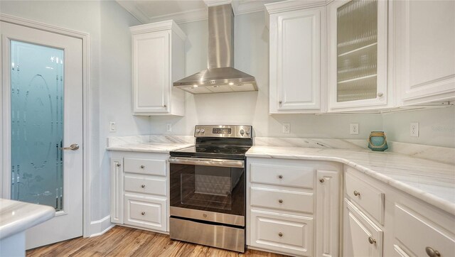 kitchen featuring white cabinetry, wall chimney range hood, stainless steel range with electric cooktop, and light wood-type flooring