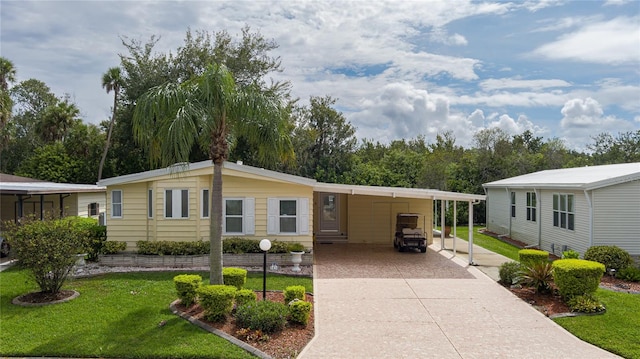 manufactured / mobile home featuring a front yard and a carport