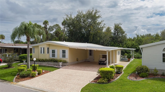 manufactured / mobile home featuring a carport and a front lawn