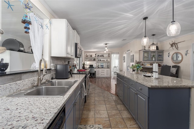 kitchen with appliances with stainless steel finishes, white cabinetry, light wood-type flooring, decorative light fixtures, and sink