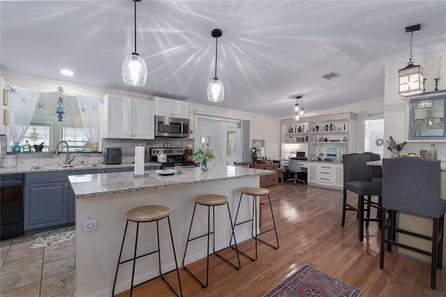 kitchen featuring white cabinetry, light stone countertops, stainless steel appliances, light wood-type flooring, and sink