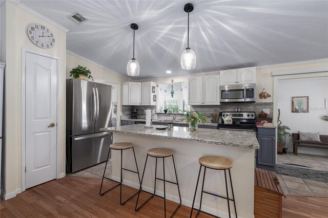 kitchen featuring light stone counters, light hardwood / wood-style floors, white cabinets, decorative backsplash, and appliances with stainless steel finishes