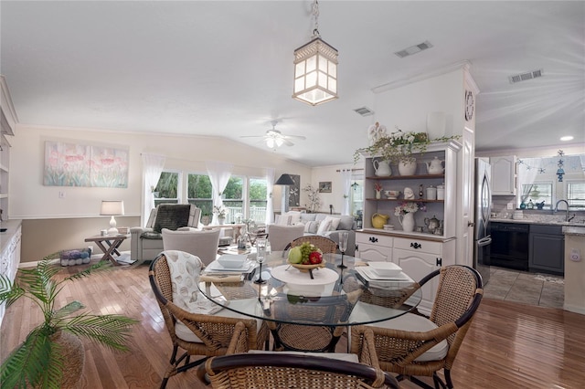 dining space featuring vaulted ceiling, light hardwood / wood-style floors, ceiling fan, and sink