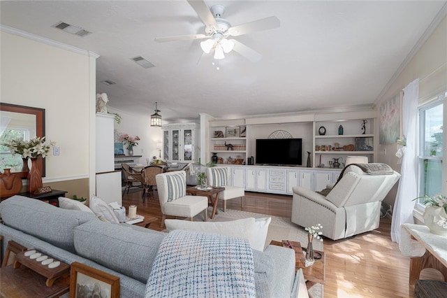 living room featuring ceiling fan, light wood-type flooring, and ornamental molding