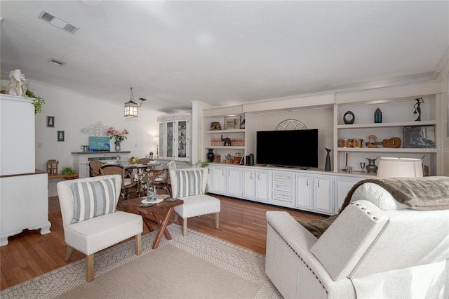 living room with light wood-type flooring and crown molding