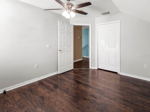 unfurnished bedroom featuring dark wood-type flooring, a closet, a textured ceiling, lofted ceiling, and ceiling fan