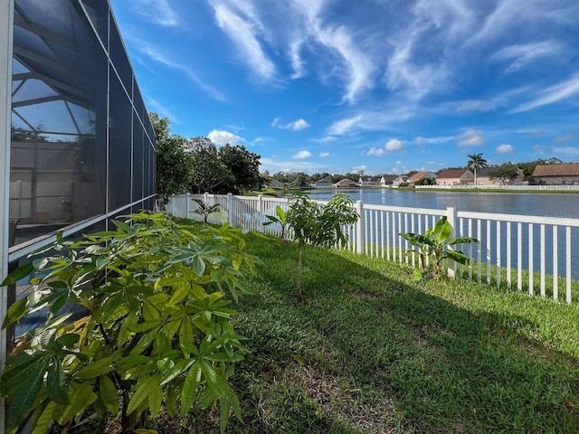 view of yard with a water view and glass enclosure