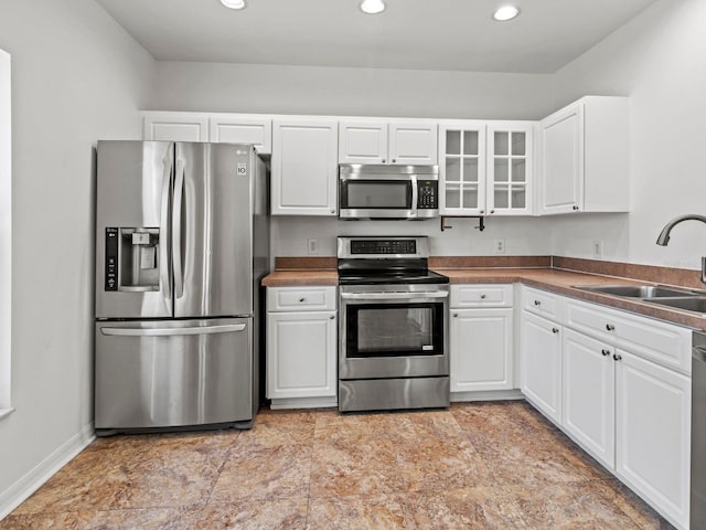 7209 49th Pl E, Palmetto, FL 34221 - kitchen featuring recessed lighting, a sink, glass insert cabinets, appliances with stainless steel finishes, and white cabinetry