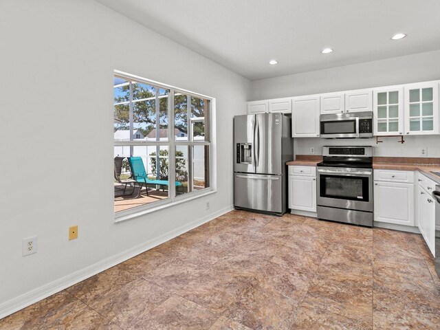 7209 49th Pl E, Palmetto, FL 34221 - kitchen with recessed lighting, baseboards, glass insert cabinets, appliances with stainless steel finishes, and white cabinetry