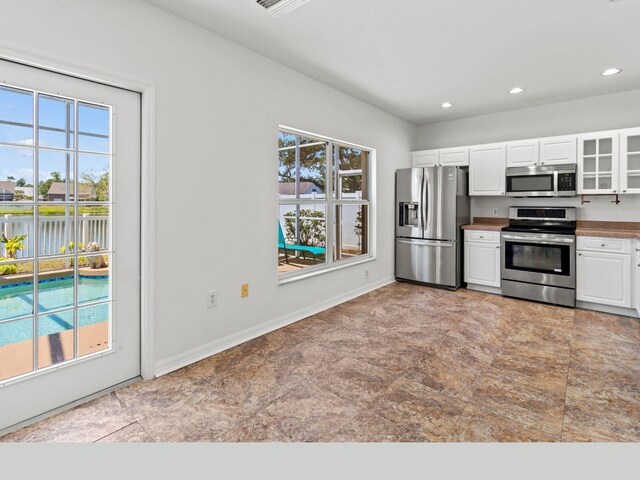 7209 49th Pl E, Palmetto, FL 34221 - kitchen with white cabinets, recessed lighting, stainless steel appliances, baseboards, and glass insert cabinets