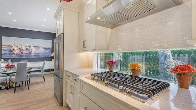 kitchen featuring light wood-type flooring, ornamental molding, extractor fan, a healthy amount of sunlight, and appliances with stainless steel finishes