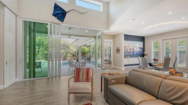 living room with ornamental molding, french doors, light wood-style floors, and a healthy amount of sunlight