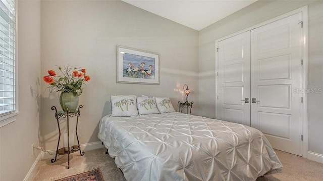 carpeted bedroom with a closet, baseboards, and lofted ceiling