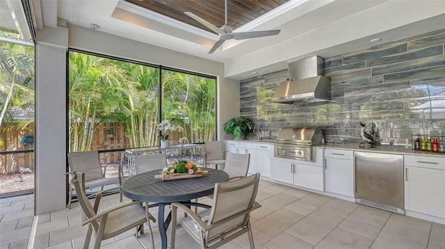 sunroom with a tray ceiling, sink, and ceiling fan