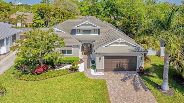 view of front of property with an attached garage, a front yard, stucco siding, and decorative driveway