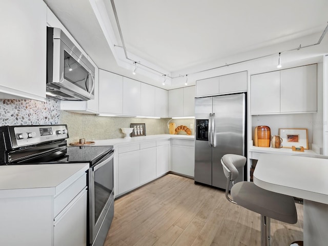 kitchen featuring white cabinets, appliances with stainless steel finishes, backsplash, and light hardwood / wood-style flooring