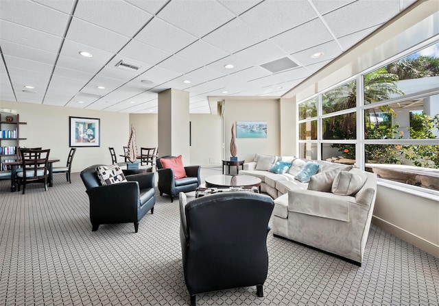 carpeted living room with a drop ceiling