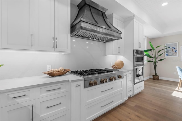 kitchen featuring white cabinetry, light hardwood / wood-style flooring, stainless steel appliances, and custom exhaust hood