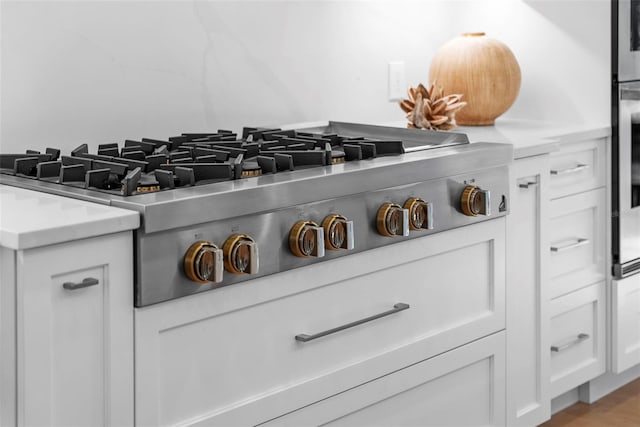 details featuring white cabinets, light wood-type flooring, and stainless steel gas cooktop