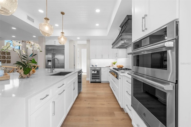 kitchen featuring beverage cooler, appliances with stainless steel finishes, white cabinets, custom range hood, and light wood-type flooring