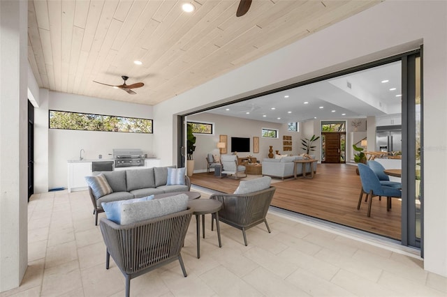 living room with ceiling fan, wood ceiling, and light hardwood / wood-style floors