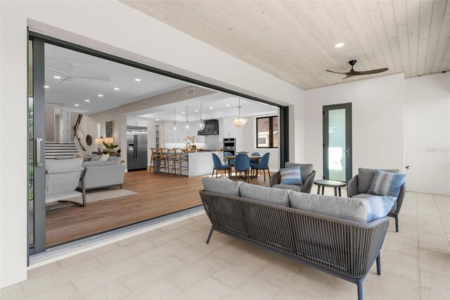 living room featuring light hardwood / wood-style flooring, ceiling fan, and wood ceiling