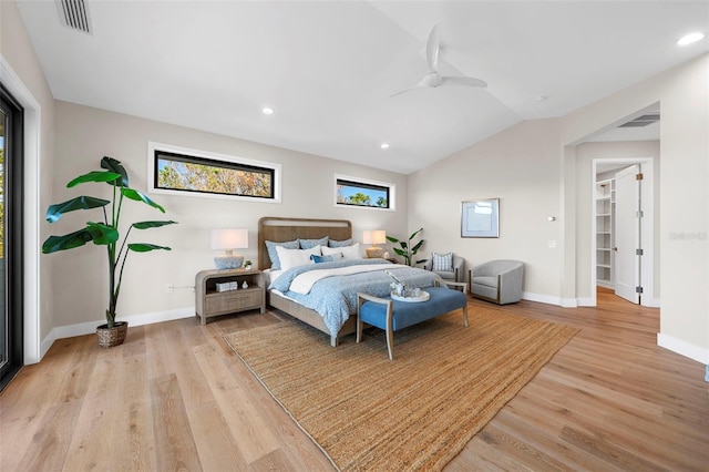 bedroom with a walk in closet, ceiling fan, light hardwood / wood-style flooring, and vaulted ceiling