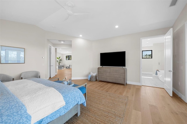 bedroom with connected bathroom, light hardwood / wood-style flooring, ceiling fan, and vaulted ceiling