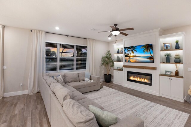 living room with a fireplace, ceiling fan, and light hardwood / wood-style flooring