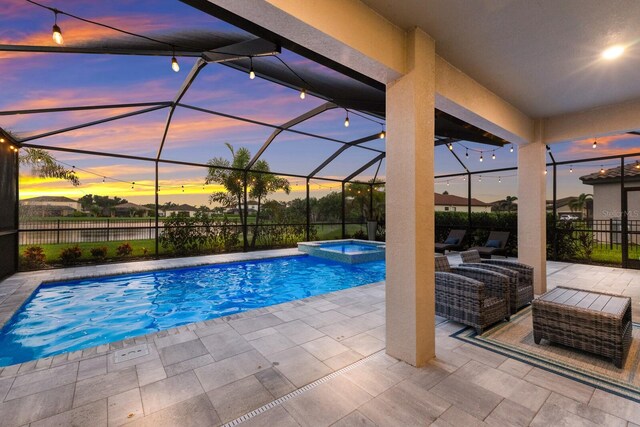 pool at dusk with a patio, glass enclosure, and an in ground hot tub