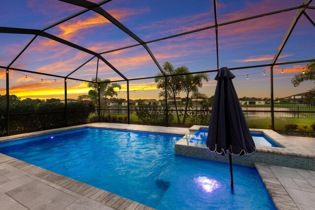 pool at dusk featuring a patio and a lanai