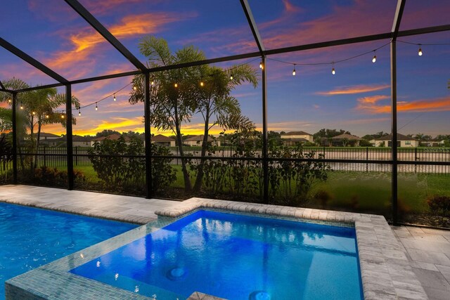 pool at dusk with a patio and a lanai