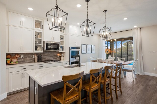 kitchen featuring appliances with stainless steel finishes, a kitchen island with sink, dark hardwood / wood-style flooring, and white cabinets