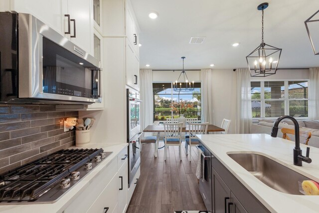 kitchen with appliances with stainless steel finishes, white cabinetry, and pendant lighting