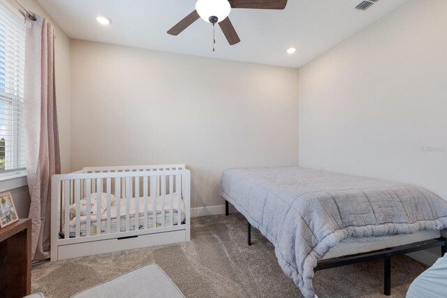 carpeted bedroom featuring multiple windows and ceiling fan