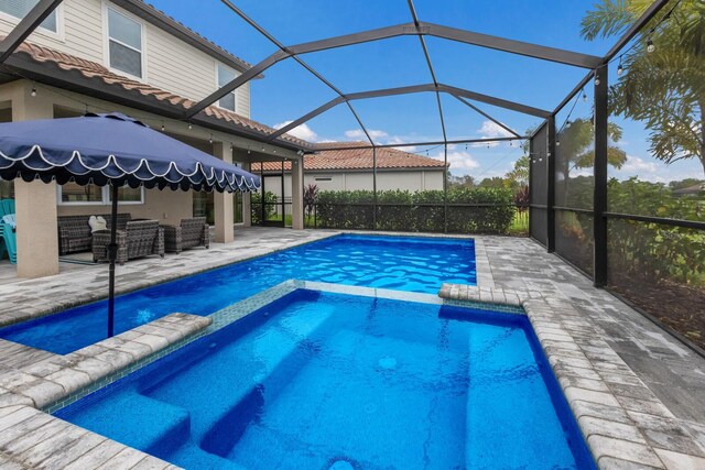 view of pool with a patio, an in ground hot tub, and a lanai