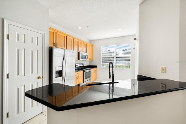 kitchen with kitchen peninsula, sink, stainless steel appliances, and light tile patterned flooring