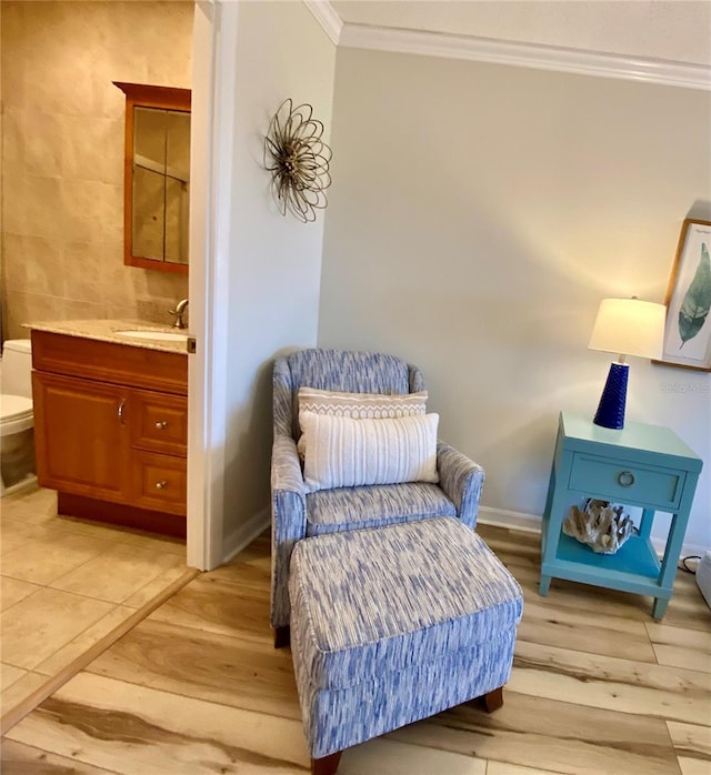 sitting room with sink, light wood-type flooring, and crown molding