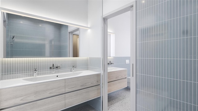 bathroom with a tile shower, tile walls, and vanity