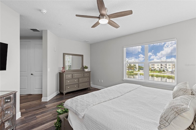 bedroom featuring a closet, ceiling fan, dark wood-type flooring, and a textured ceiling