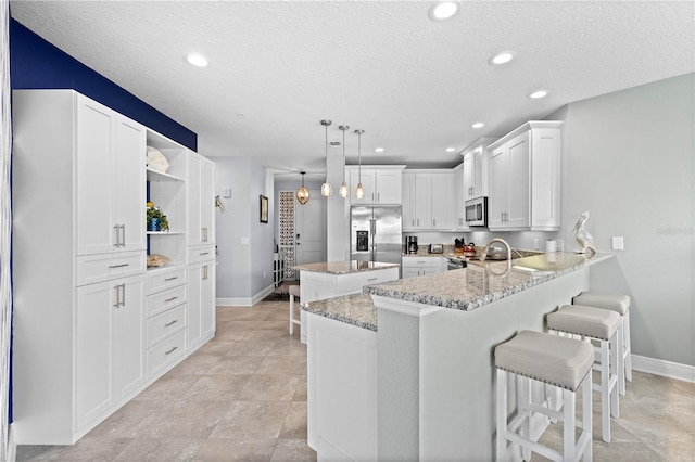 kitchen with a textured ceiling, white cabinetry, kitchen peninsula, appliances with stainless steel finishes, and decorative light fixtures