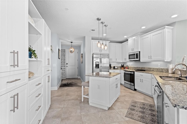 kitchen featuring white cabinets, appliances with stainless steel finishes, sink, and a center island